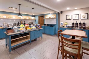 A kitchen with blue cabinets, a central island with food items, and a coffee station.
