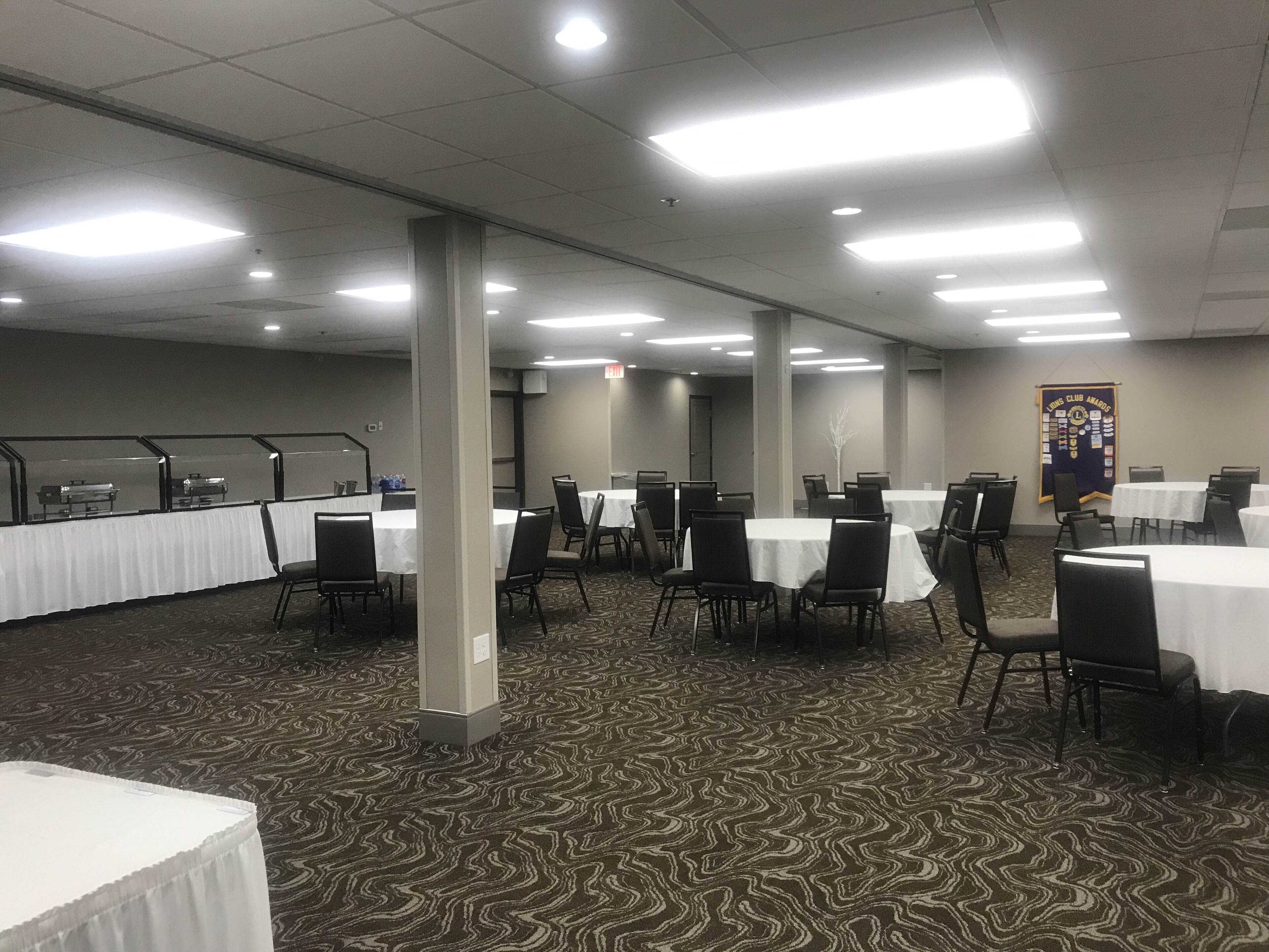 A conference room with multiple tables and chairs, arranged in rows.