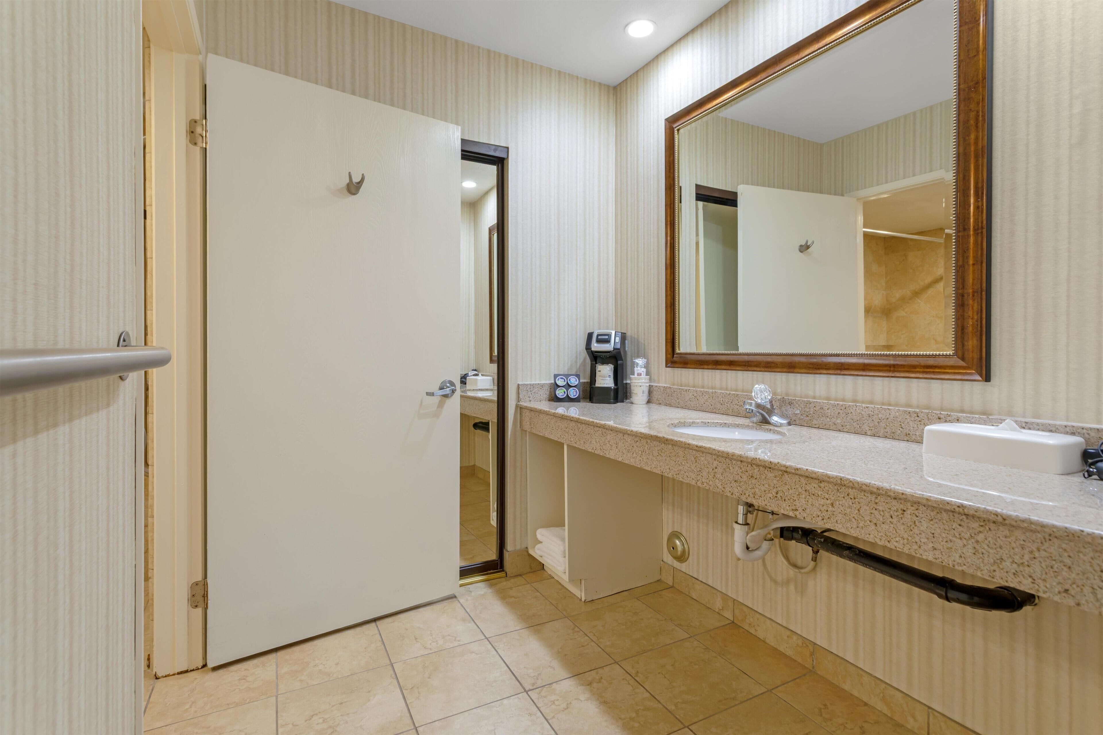 Une salle de bain équipée d’un lavabo, d’un miroir, d’un porte-serviettes et d’une porte donnant sur une autre pièce.
