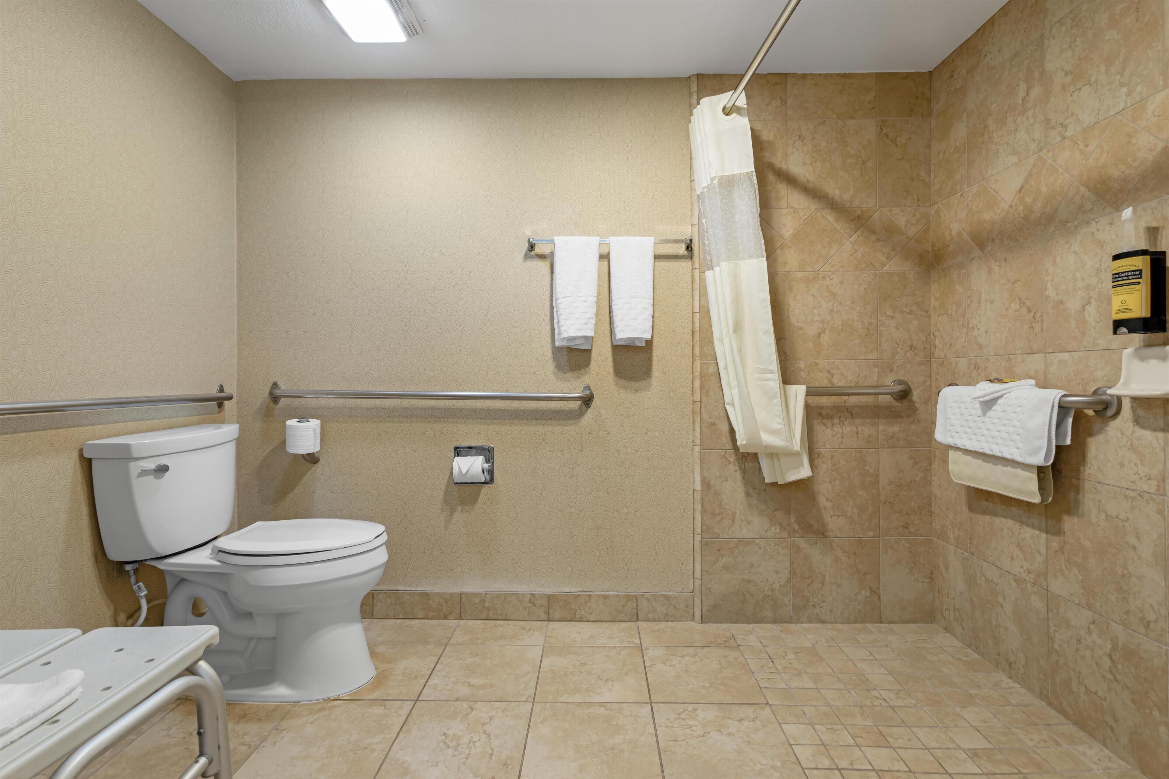 Une salle de bain comprenant des toilettes, une douche avec une porte en verre et un porte-serviettes avec plusieurs serviettes.