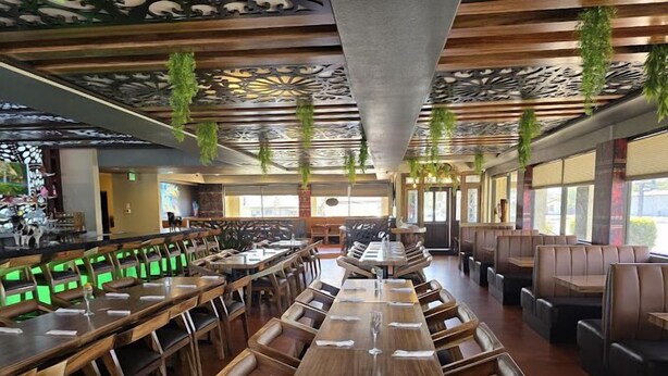 A restaurant with long wooden tables and booths, hanging plants, and a decorative ceiling. - Best Western Plus Big America (Santa Maria)