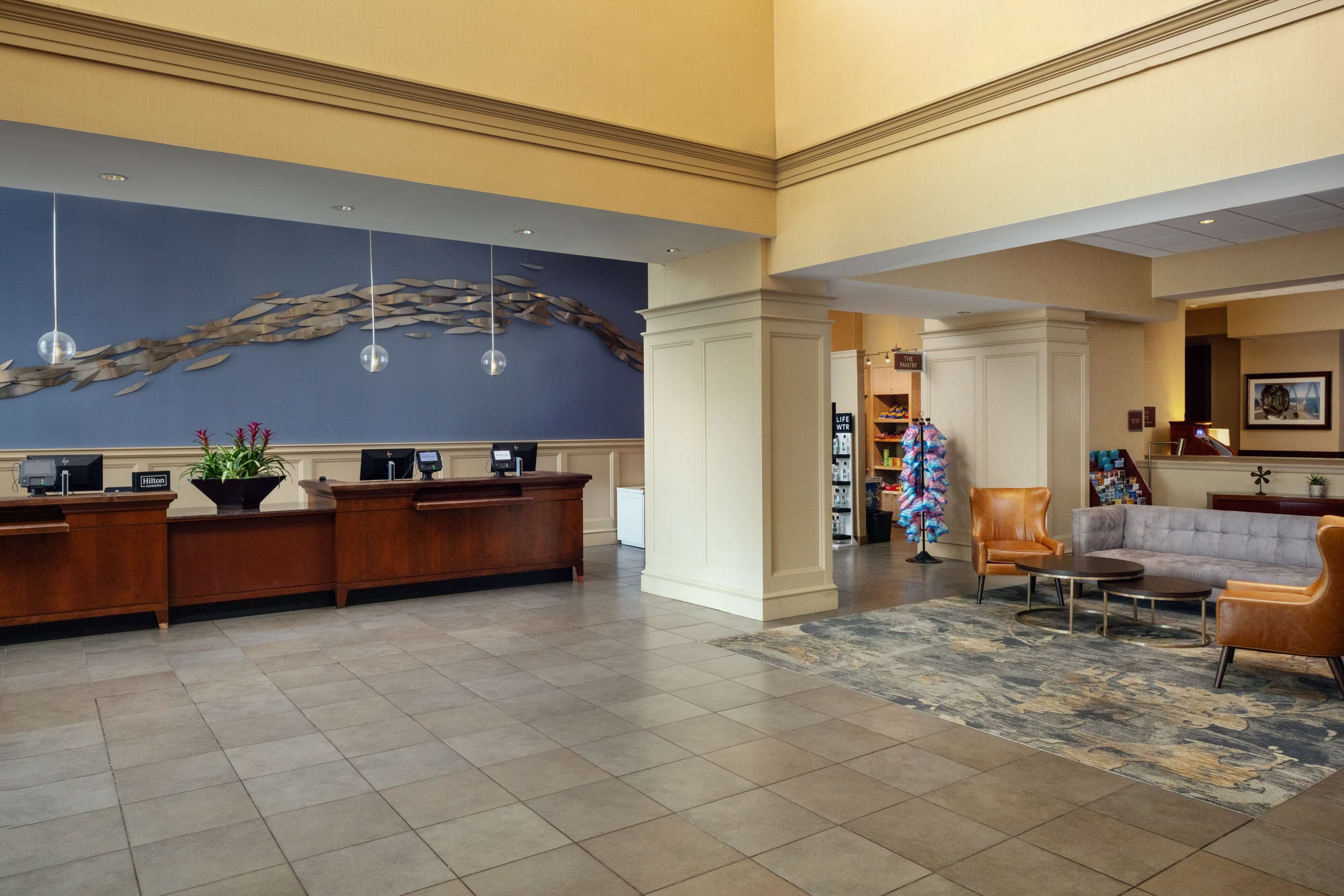 Een hotel lobby met een receptiebalie, een zithoek en een decoratieve wand.