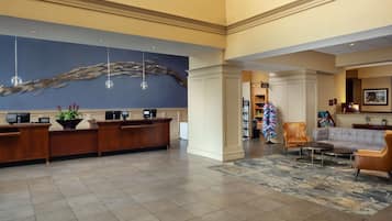 Een hotel lobby met een receptiebalie, een zithoek en een decoratieve wand.
