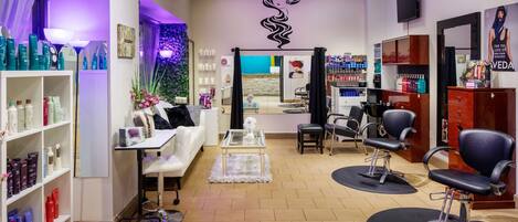 A salon interior with shelves of hair products, a reception area, and multiple salon chairs.