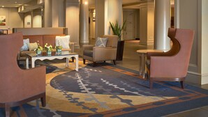 Eine Lobby mit einer Couch, Sesseln, einem Couchtisch und einer Zimmerpflanze.