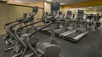 Ein Fitnessstudio mit Laufbändern, Crosstrainern und Fahrrädern.