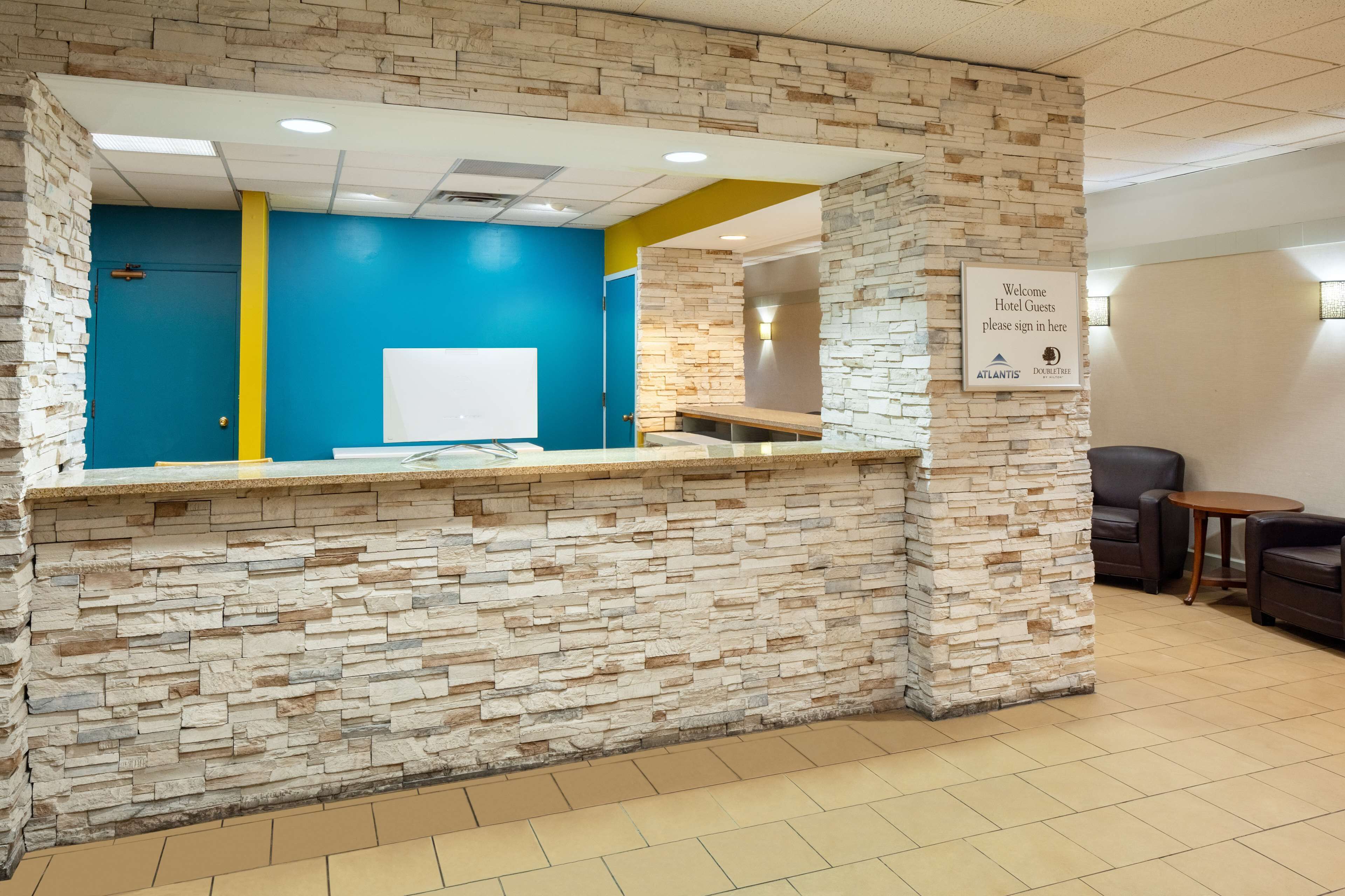 A reception area with a stone wall, a blue accent wall, and a sign for hotel guests to sign in.