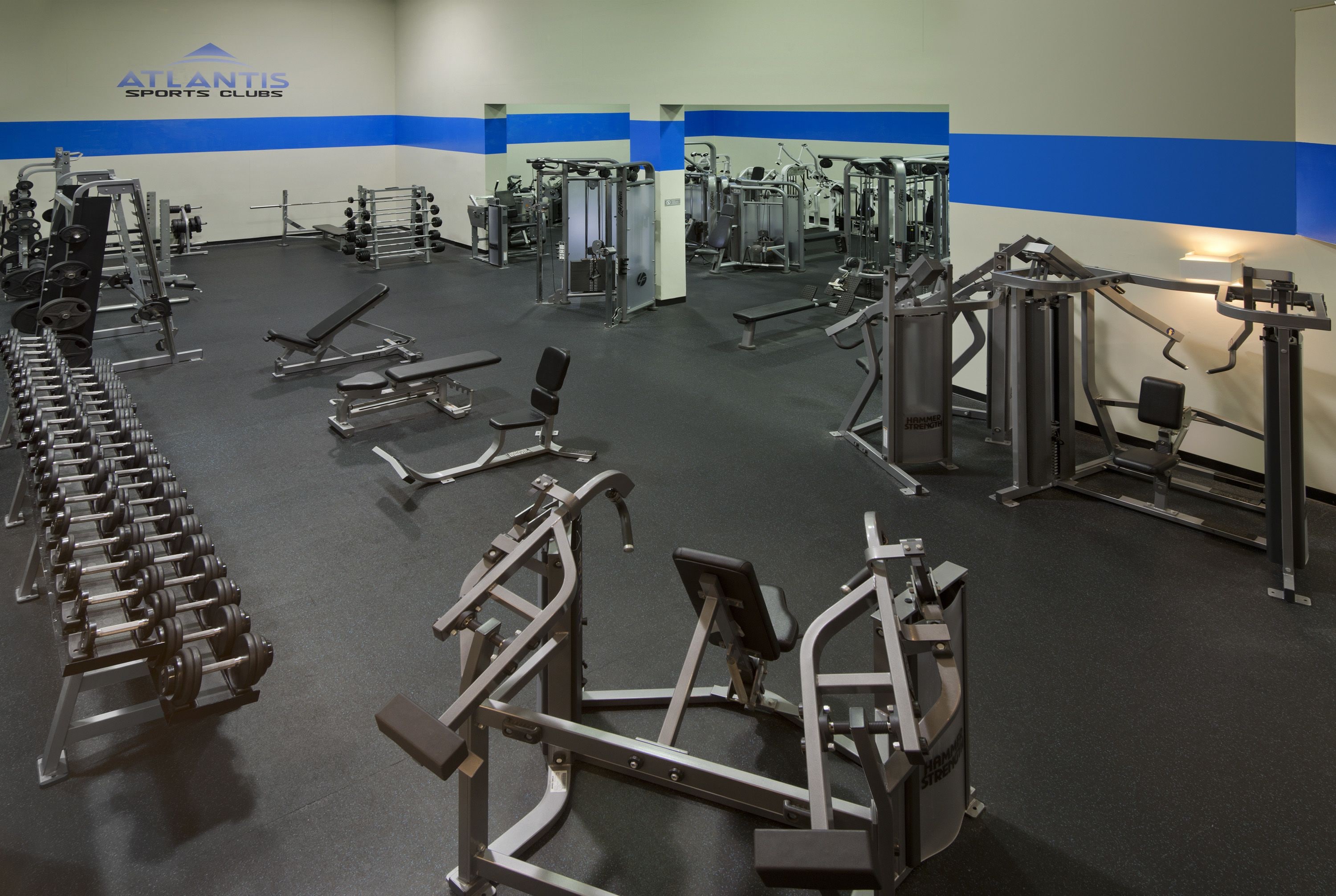 A gym with various exercise equipment, including dumbbells, benches, and weight machines.