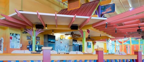 Un restaurante vibrante con arquitectura colorida, que destaca un techo distintivo y barandillas onduladas.