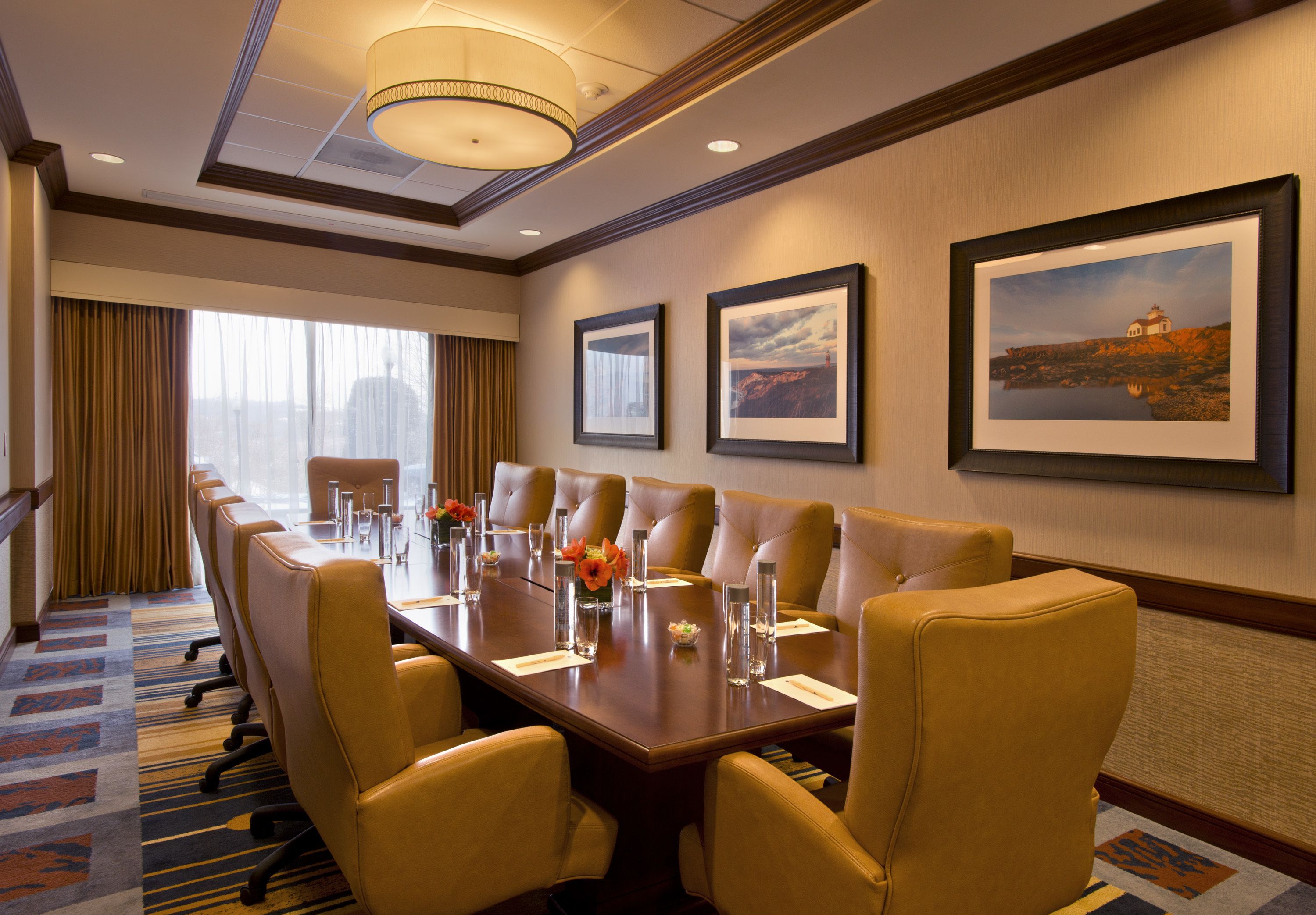 A conference room with a long table, multiple chairs, and framed pictures on the wall.