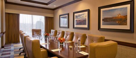A conference room with a long table, multiple chairs, and framed pictures on the wall.