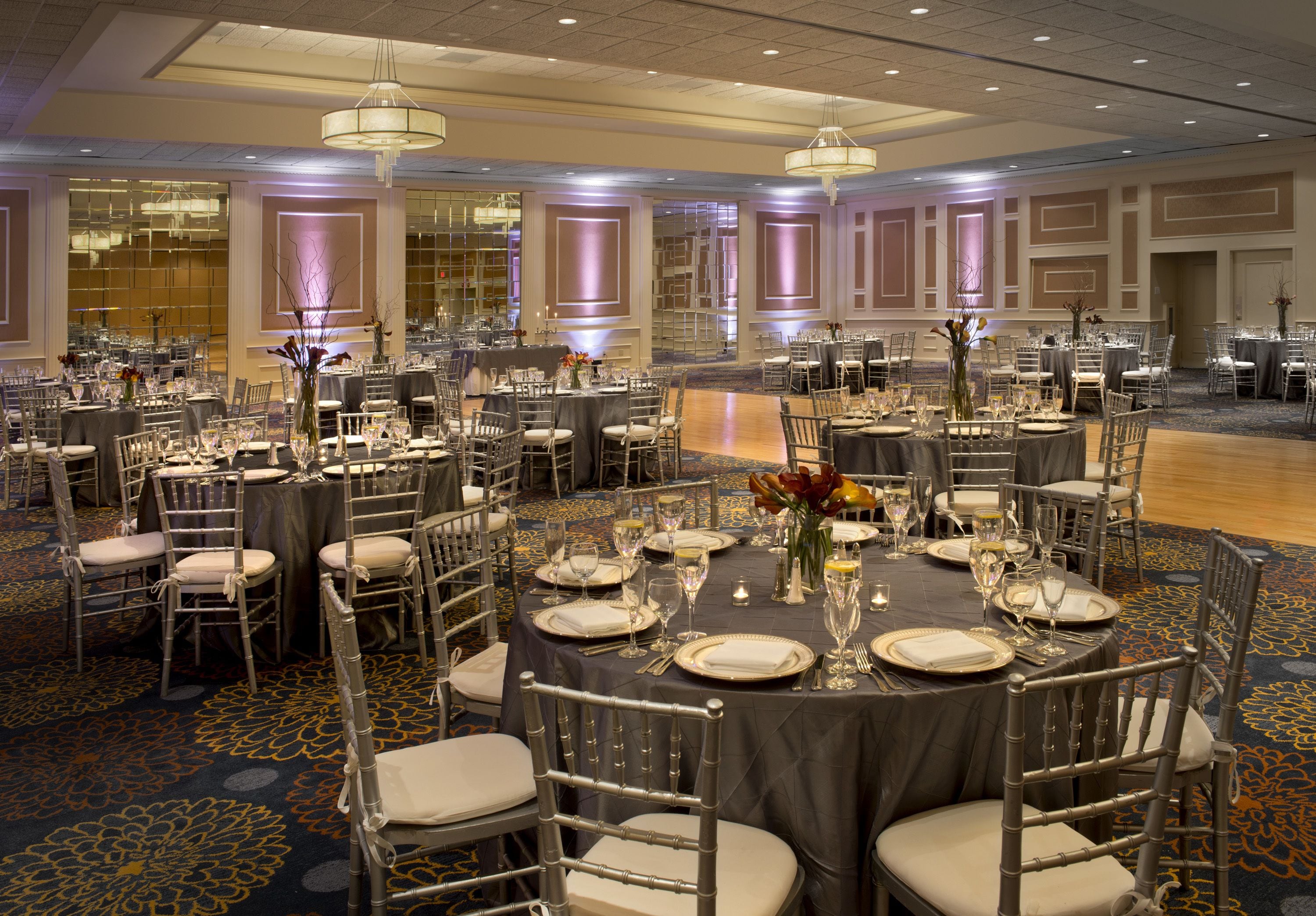 Une salle de banquet avec des tables rondes, des chaises et des lustres.