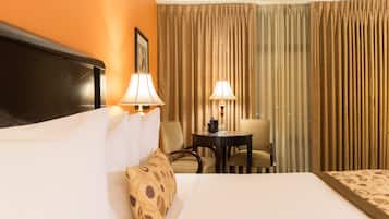 Una habitación de hotel con una cama, dos sillas, una mesita y una lámpara.