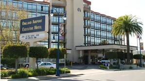 L’extérieur de l’hôtel Oakland Airport Executive présente une façade claire, une architecture moderne et des espaces verts bien entretenus.