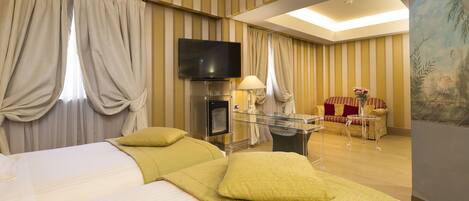 A hotel room with a large bed, a TV, a seating area with a sofa and armchairs, and a painting on the wall.