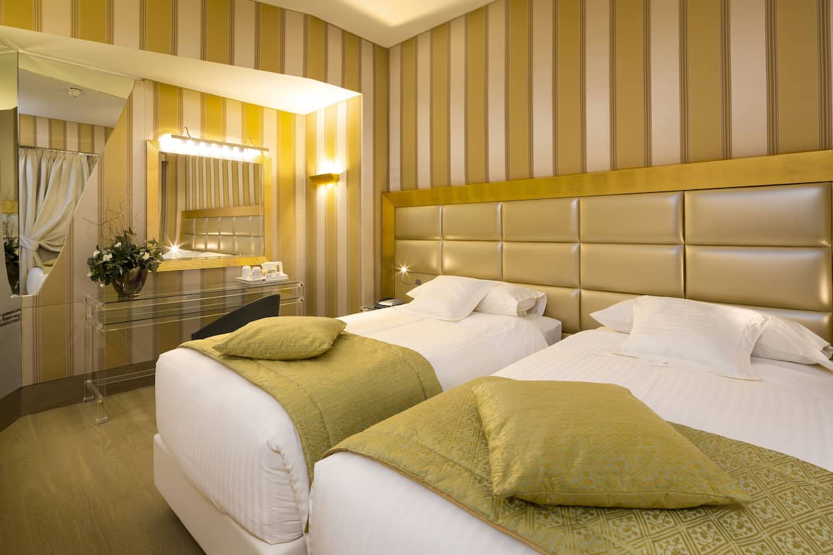 A hotel room with two beds, a large mirror, and a vanity with a sink.
