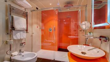 Un baño moderno con ducha envuelta en vidrio, dos lavamanos y un espejo grande.