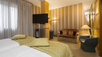 Une chambre d’hôtel avec un grand lit, un canapé, une télévision et un bureau avec une lampe.