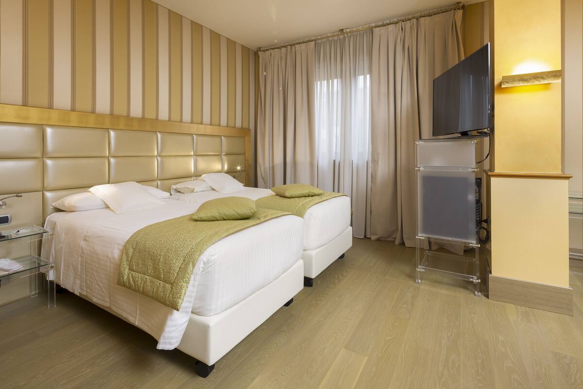 A hotel room with a large bed, a TV, and a minibar.