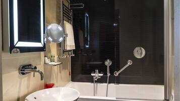Une salle de bain moderne dotée d’une grande baignoire, d’un lavabo séparé et d’un espace douche.
