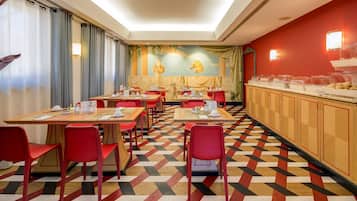 Ein Restaurant mit roten Stühlen und Tischen, einem gemusterten Boden und einem Buffetbereich mit Speisebehältern.