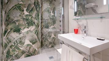 Une salle de bain moderne avec une douche à l’italienne en verre, une baignoire blanche et un meuble-lavabo avec un miroir.