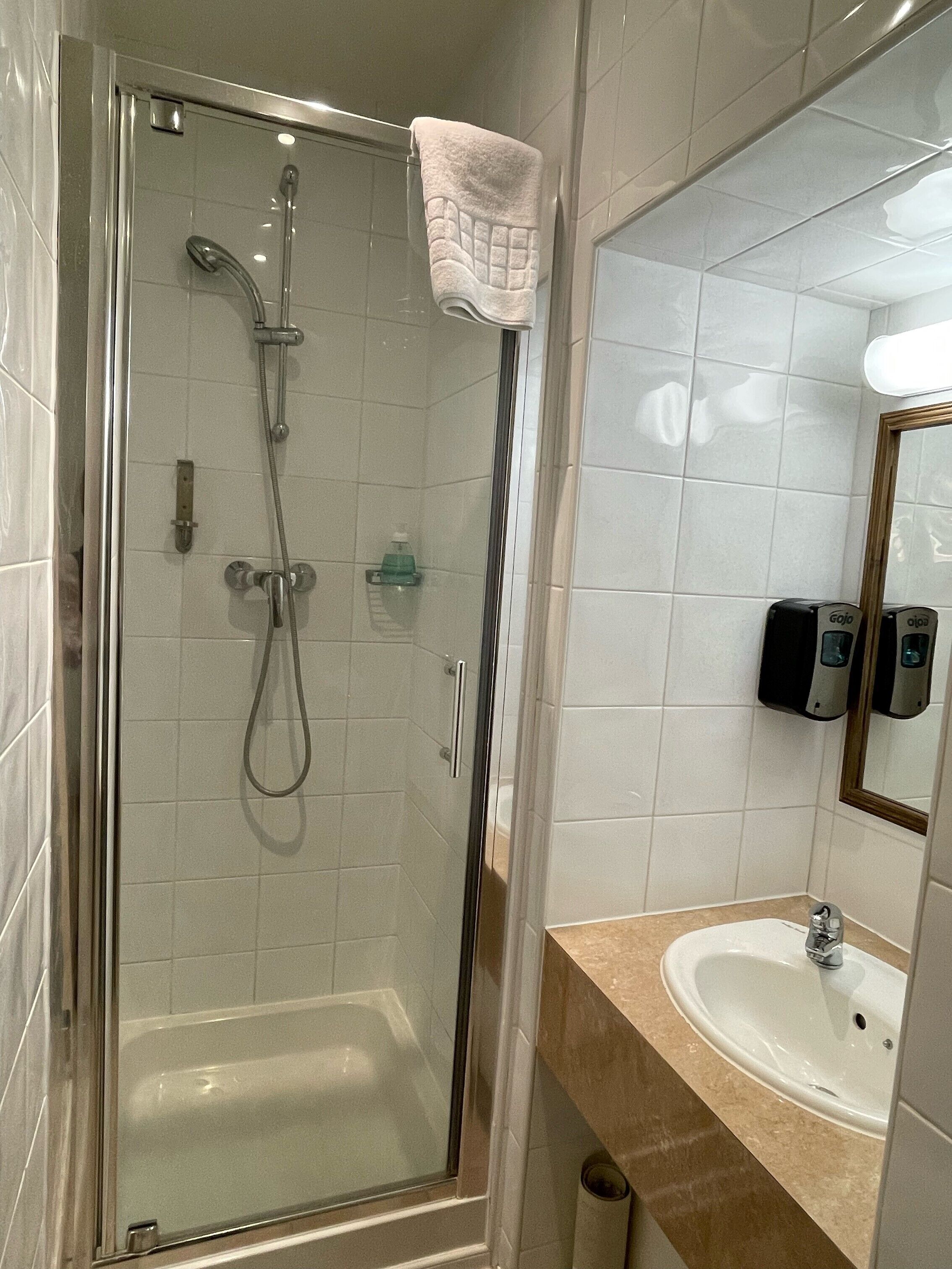 A modern bathroom with a glass-enclosed shower, a sink, and a hand dryer.