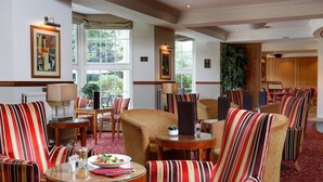 Un vestíbulo de hotel con sillones a rayas, mesas redondas y una zona de comedor.