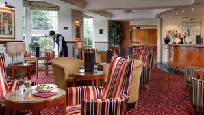Un vestíbulo de hotel con sillas a rayas, una zona de comedor y un bar.