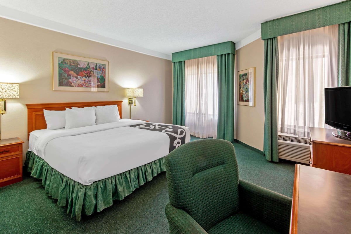 Ein Hotelzimmer mit einem großen Bett, einem Schreibtisch mit Fernseher und einem Sessel.