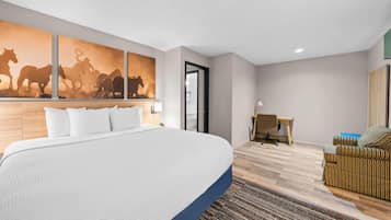 Habitación de hotel con una cama grande, un escritorio, una silla y un cuadro de caballos colgado en la pared.