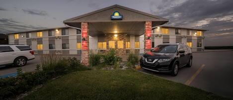 Ein Days Inn Hotel mit Parkplatz, einem weißen Auto und einem schwarzen SUV.