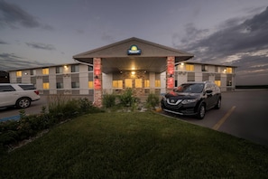 Ein Days Inn Hotel mit Parkplatz, einem weißen Auto und einem schwarzen SUV.