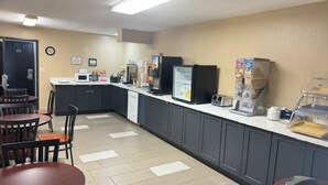 Een kitchenette voorzien van een magnetron, broodrooster, koelkast en koffiezetapparaat.