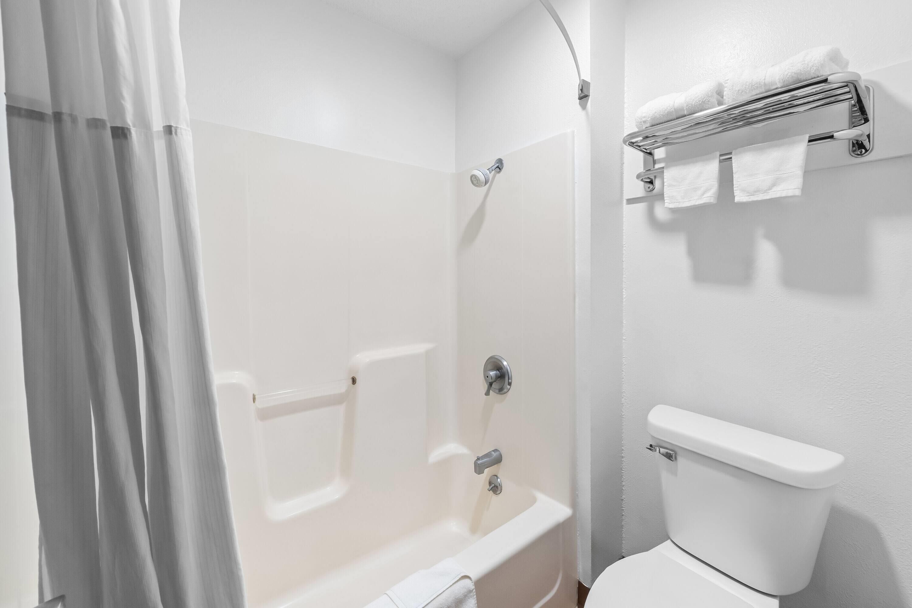 A bathroom with a bathtub, toilet, and towel rack.