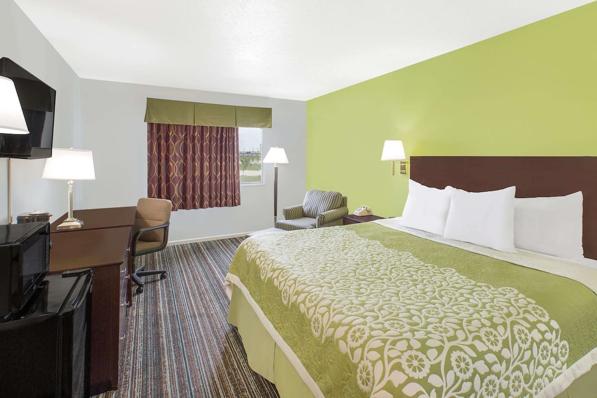 A hotel room with a bed, desk, chair, and television.
