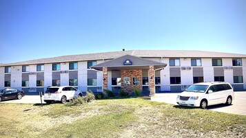 A Days Inn with a brick facade, multiple windows, and a parking lot with several cars.