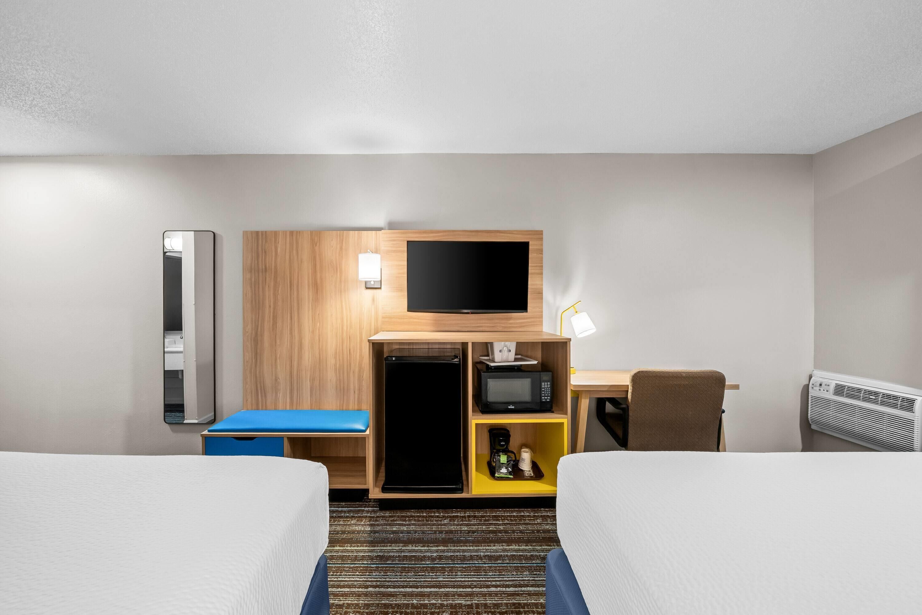 Habitación de hotel con dos camas, un escritorio, televisión de pantalla plana, microondas y cafetera.