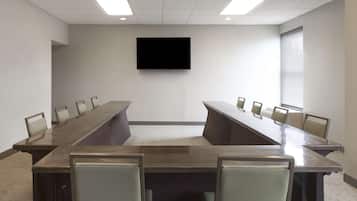 A conference room with a long table, chairs, a flat-screen TV, and a carpeted floor.