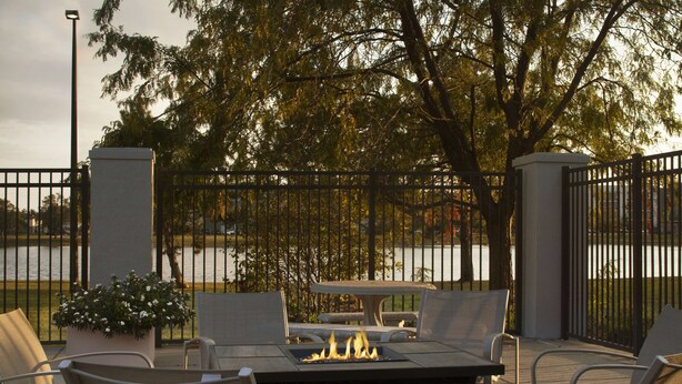 Un patio exterior con una chimenea, asientos y vistas a un lago.
