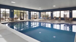 Una piscina con agua azul cristalina, rodeada de sillones y mesas.