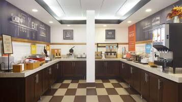 Un espace dédié au petit-déjeuner, avec un sol à carreaux, des meubles en bois et une variété d’aliments présentés pour le petit-déjeuner.