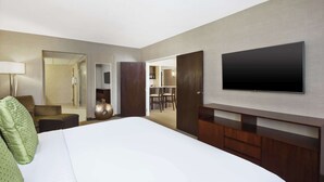 A hotel room with a large bed, a TV mounted on the wall, a desk, and a chair.