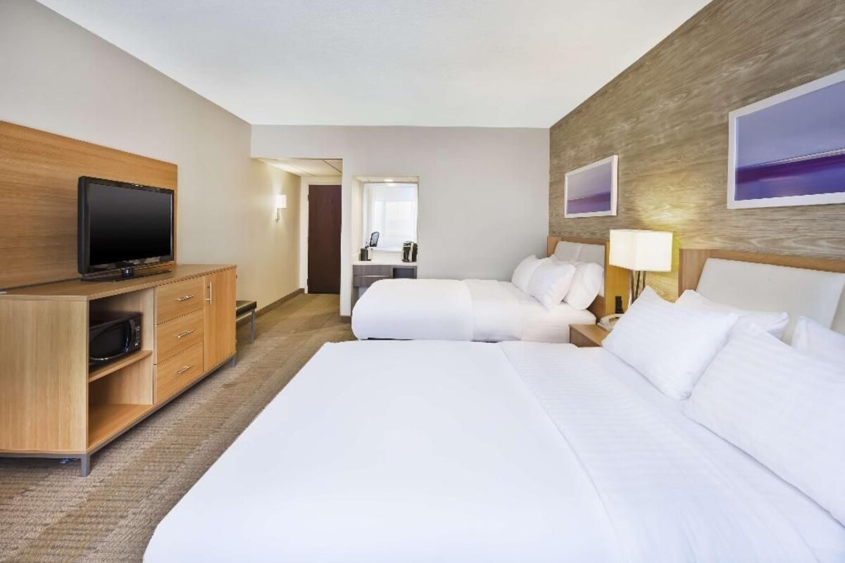 Een hotelkamer met twee bedden, een televisie, een bureau en een spiegel.