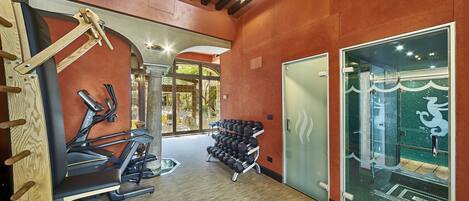 A gym with treadmills, dumbbells, and a glass door leading to a pool area.
