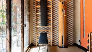 Une pièce avec un mur orné d’un motif géométrique, un banc noir, une échelle en bois et un meuble en bois.