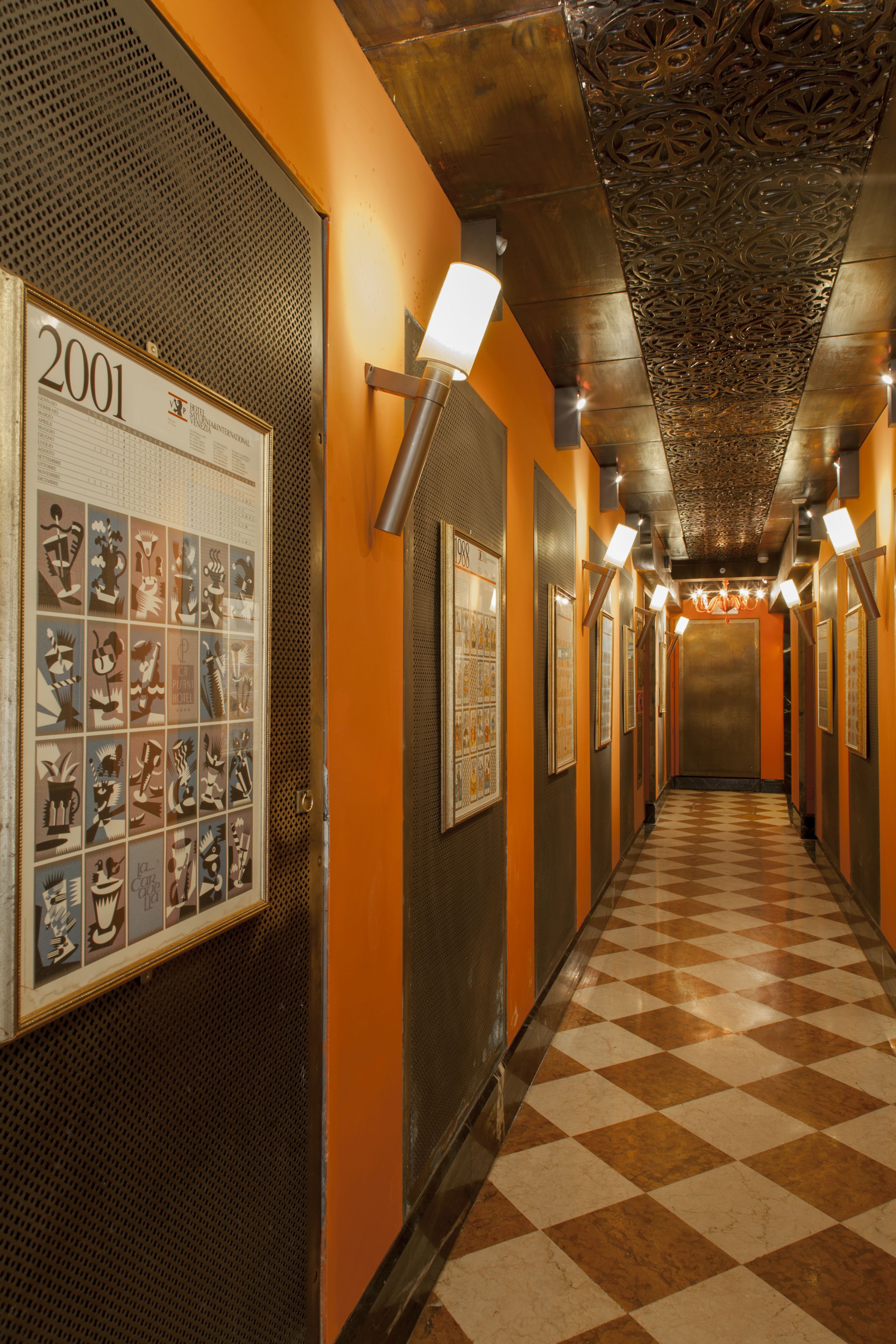 A hallway with a checkered floor, framed artwork on the walls, and a year sign.
