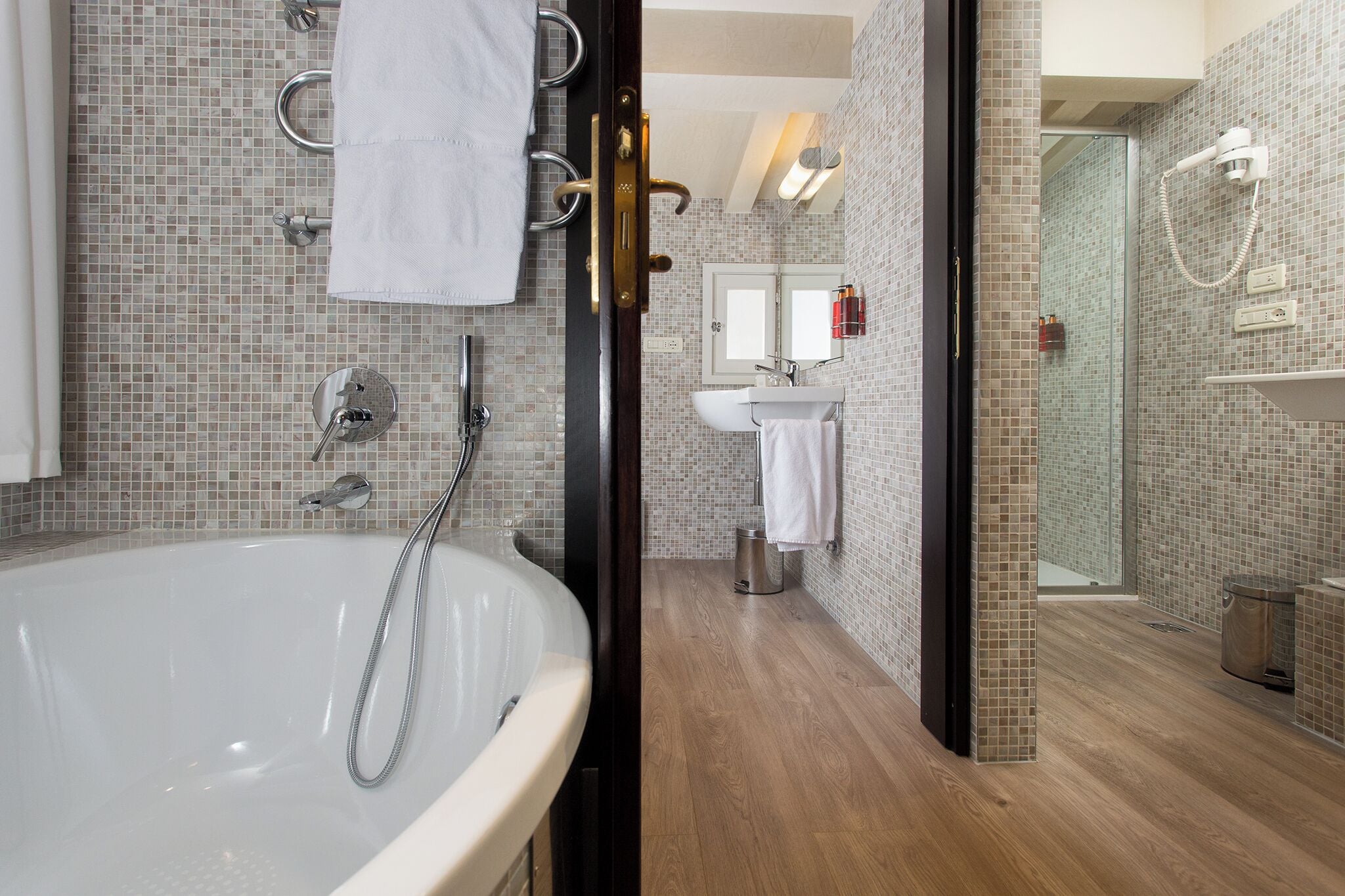 Un bagno moderno con una vasca da bagno spaziosa, una doccia, un lavandino e uno specchio.