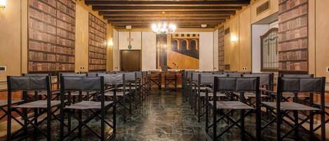 Un salón de conferencias con filas de sillas, techo de madera y estanterías a ambos lados.