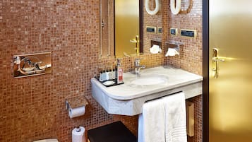 Un bagno con pavimento piastrellato, un lavandino, un water e uno specchio.